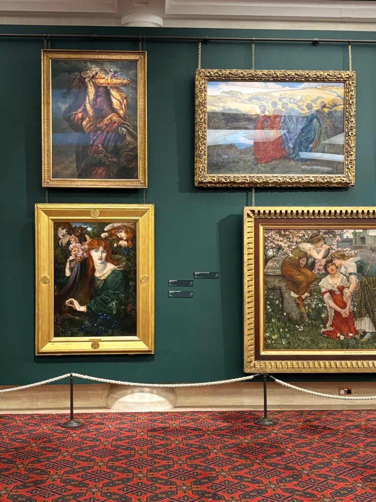 緑の壁に飾られた4つの絵画。上の左に肖像画、上の右に風景画、下の左に女性の肖像画、下の右に人々が描かれた絵。