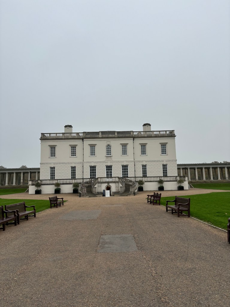 白い外観の建物とその前の芝生とベンチの風景