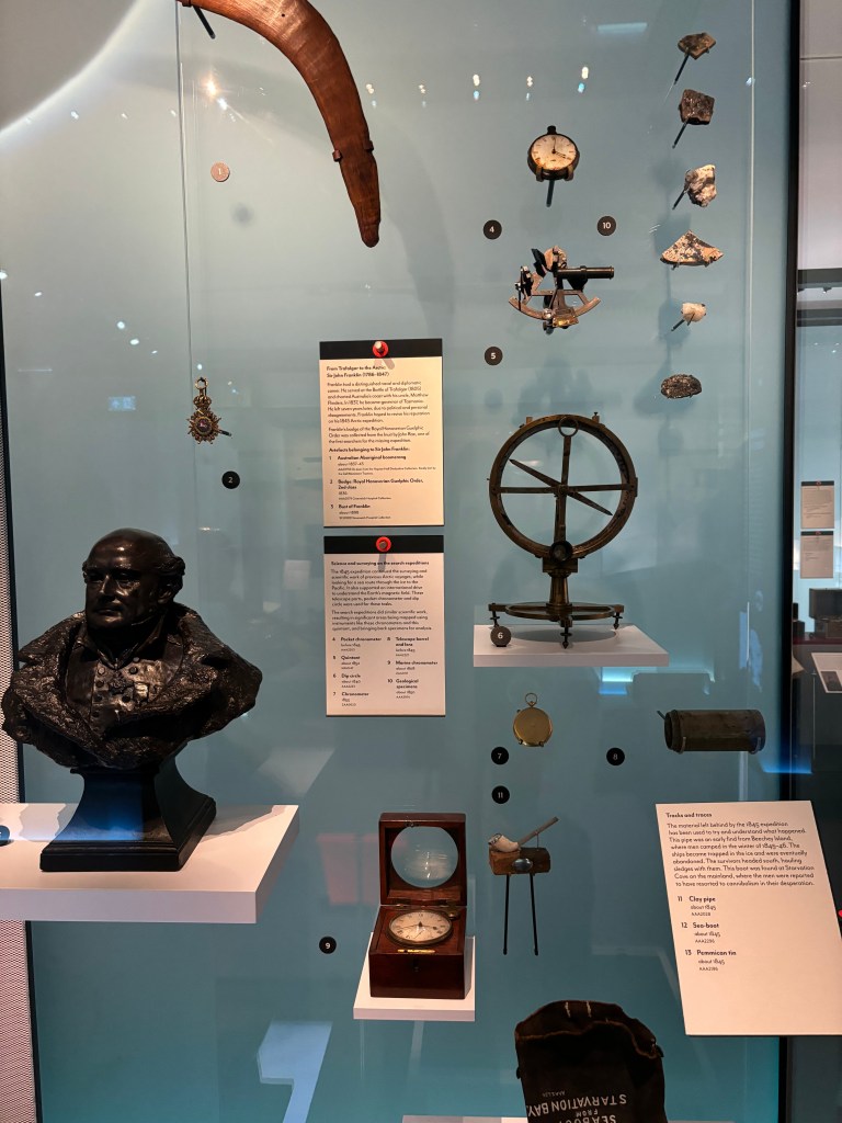 展示された様々な歴史的な道具や標本、胸像、説明文が並んでいる展示ケースの画像。